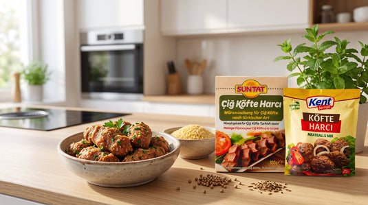 Bol de boulettes de kefta crues assaisonnées posé à côté des sachets d'épices SUNTAT Çiğ Köfte Harcı et KENT Köfte Harcı sur un plan de travail de cuisine