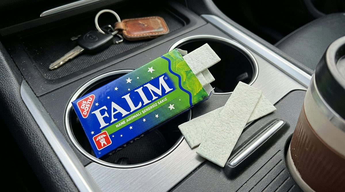 Paquet de chewing-gum à la menthe sans sucre FALIM 140g posé sur la console d'une voiture à côté d'un trousseau de clés