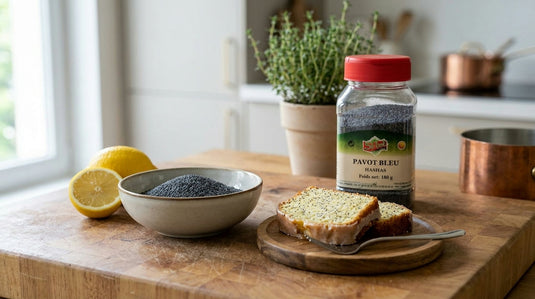 Bol de graines de pavot bleu à côté d'une tranche de cake citron-pavot et du pot de graines de pavot SIBEL sur un plan de travail en bois