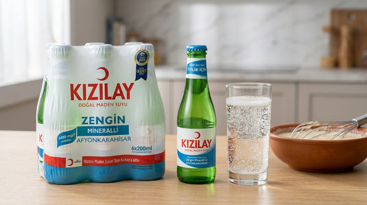 Pack et bouteille d'eau gazeuse KIZILAY posés à côté d'un verre d'eau pétillante et d'un bol de pâte à frire en préparation, dans une cuisine moderne