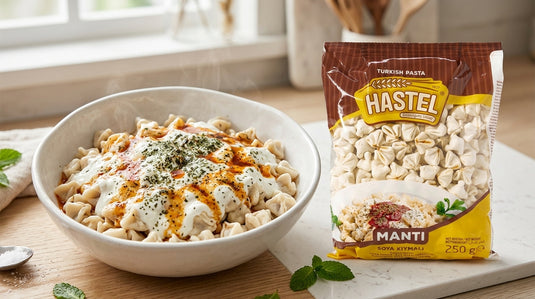 Bol de mantı nappé de sauce au yaourt à l'ail et de beurre pimenté, à côté d'un paquet de manti HASTEL sur un plan de travail de cuisine