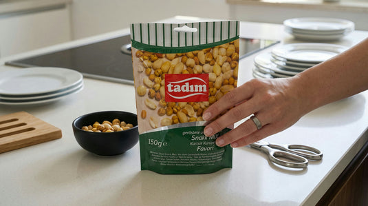 Sachet du Mélange de Noix, Pois Chiches et Maïs Grillés TADIM à côté d'un bol du mélange servi à l'apéro, sur un plan de travail de cuisine moderne