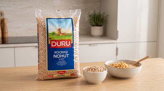 Sac de pois chiches secs 5kg DURU posé à côté d'un bol de pois chiches trempés sur un plan de travail en bois