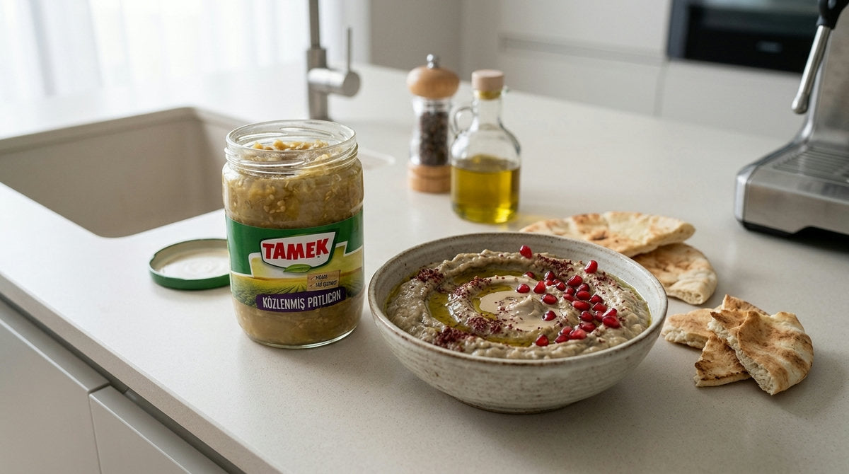 Bocal d'aubergines grillées TAMEK à côté d'un bol de tartinade façon babaganoush garnie de grenade et de sumac, avec du pain pita