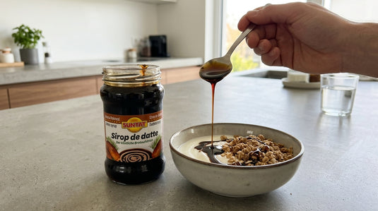 Pot de sirop de datte SUNTAT 390g posé à côté d'un bol de granola et yaourt nappé de sirop, dans une cuisine moderne
