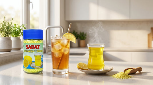 Verre de thé glacé au citron avec glaçons à côté d'une tasse de thé chaud fumante et du pot SARAY Keskin Limon