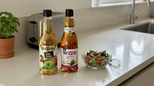 Bouteilles de vinaigre de cidre et de vinaigre de raisin DOGANAY posées à côté d'un bol à salade sur un plan de travail de cuisine moderne