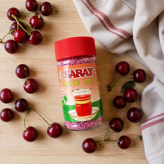 Thé instantané à la cerise SARAY Vişne Çayı 200g - vue flat lay avec cerises fraîches